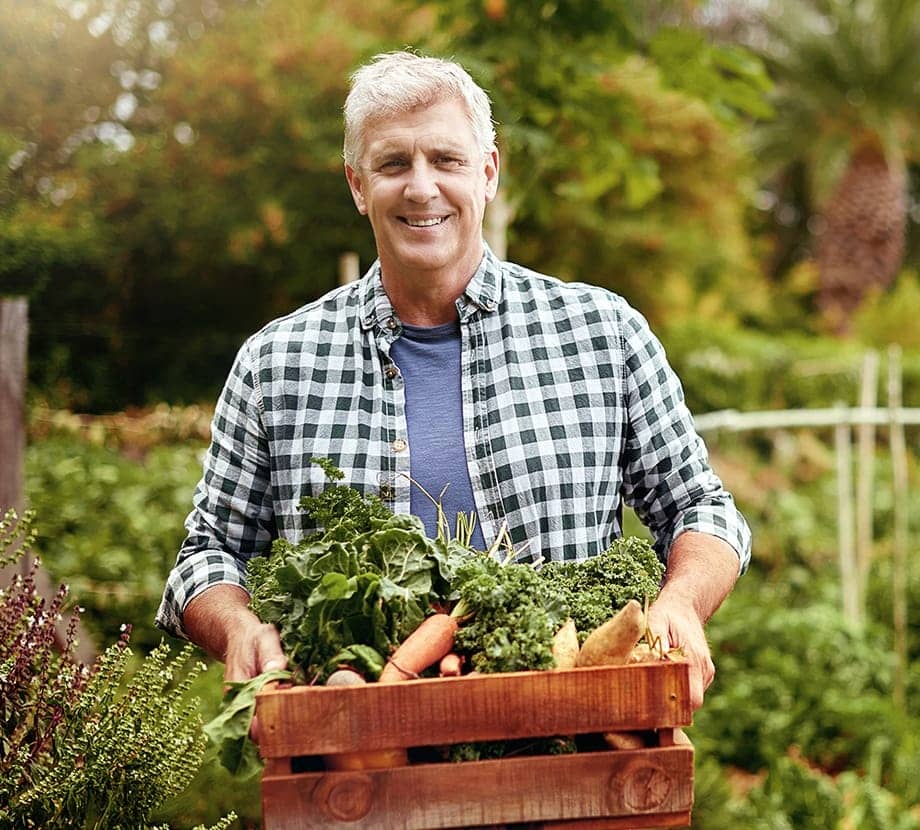 Image of a smiling man with a box of vegetables in his hands
