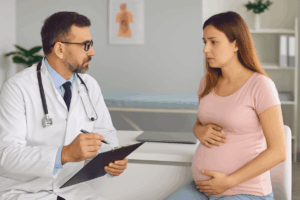 Pregnant woman consulting with a doctor about Hemorrhoids During Pregnancy in a medical office.